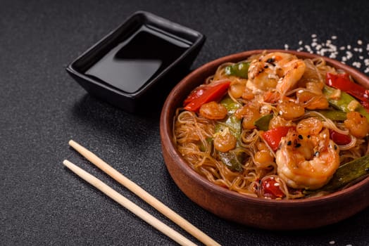 Glass noodles with shrimps and seafood, vegetables, spices and soy sauce on dark concrete background