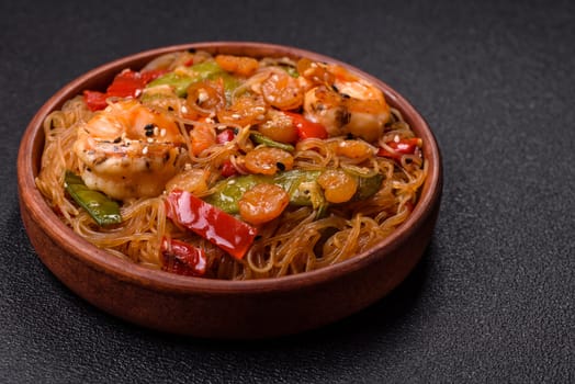 Glass noodles with shrimps and seafood, vegetables, spices and soy sauce on dark concrete background