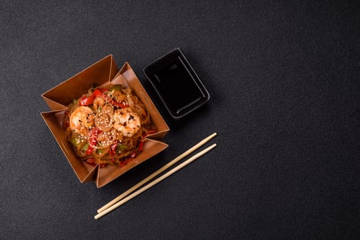 Glass noodles with shrimps and seafood, vegetables, spices and soy sauce on dark concrete background