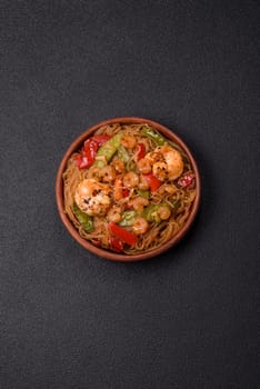 Glass noodles with shrimps and seafood, vegetables, spices and soy sauce on dark concrete background