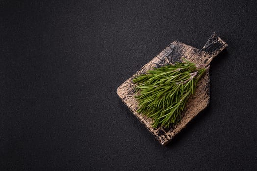 Fresh green rosemary sprigs prepared for cooking, on dark concrete background