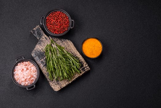 Fresh green rosemary sprigs prepared for cooking, on dark concrete background