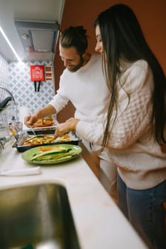 A couple joyfully and enthusiastically preparing a delicious meal together in their stylish and cozy kitchen