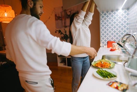 A loving couple is sharing their quality cooking time together in a cozy and inviting kitchen space