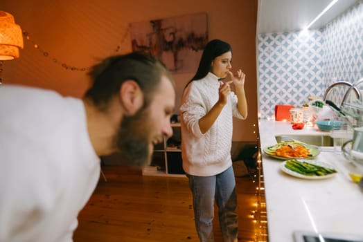 A couple enjoys a joyful moment in their cozy kitchen, surrounded by delicious food and warm, lovely lighting