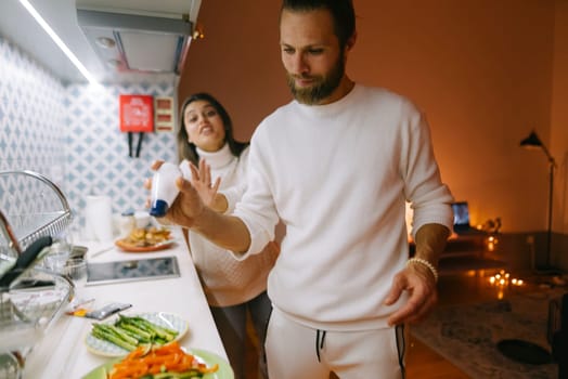 A cheerful couple joyfully preparing a delicious meal together in a warm and inviting kitchen environment