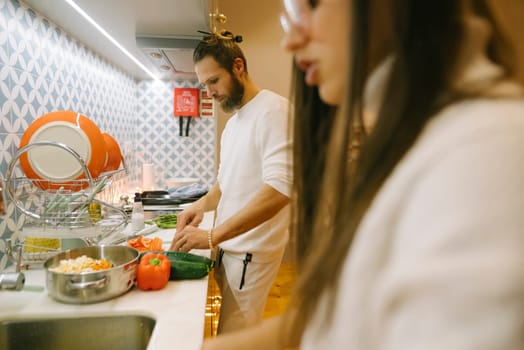 A couple is preparing a variety of fresh ingredients for a meal in their stylish and modern kitchen space
