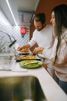 A joyful couple is happily cooking together in their beautiful, modern kitchen, showcasing their love and teamwork