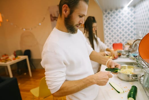 A man skillfully prepares a fresh cucumber in his modern kitchen, creating a warm, inviting cooking experience