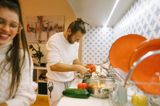 A joyful couple prepares a meal together in a stylish kitchen, showcasing teamwork and culinary skills.