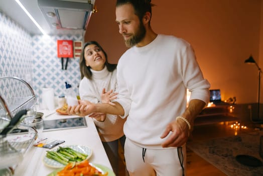 A couple enjoys a fun cooking session in their beautifully styled kitchen full of fresh ingredients