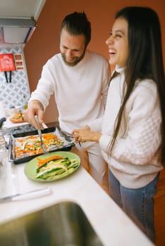 A cheerful couple joyfully prepares a delicious meal together, happily enjoying their quality time in the kitchen