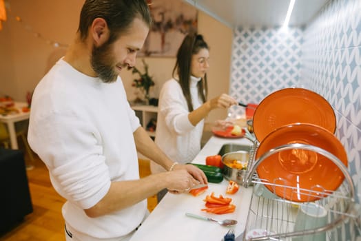 A couple joyfully prepares fresh ingredients in their stylish kitchen, showcasing teamwork and culinary creativity.
