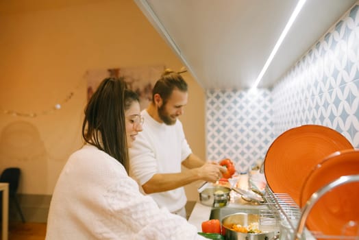 A couple happily enjoys cooking together in a stylish, welllit kitchen, creating cherished memories together