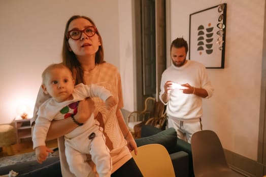 In a cozy and warm home setting, a loving mother gently holds her baby, while another adult engages with a phone