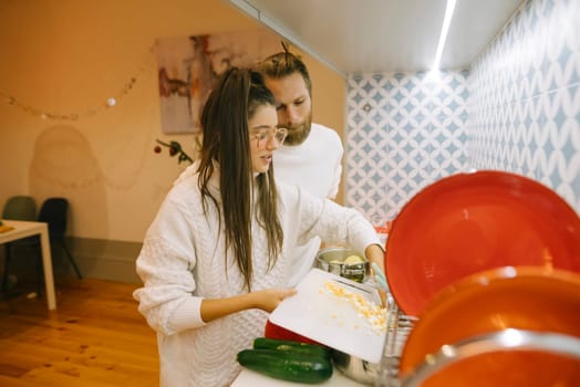 A couple happily enjoys cooking together in their stylish kitchen, which is filled with fresh, vibrant ingredients