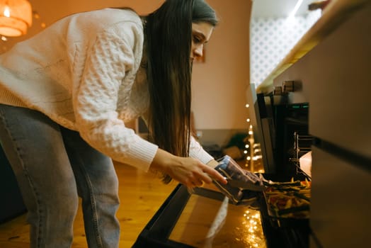 A woman pours fresh, colorful ingredients into the oven in a stylish kitchen that radiates comfort and elegance