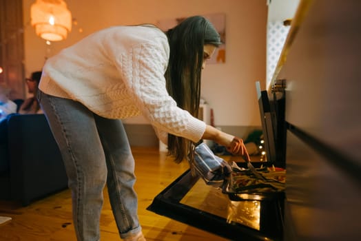 A woman checks the oven while she is cooking a delicious meal, showcasing a warm and inviting kitchen atmosphere