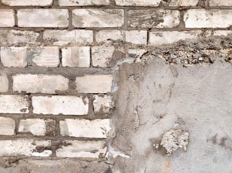 Close-up view of a textured wall with a combination of brick and plaster, providing a versatile background for design projects.