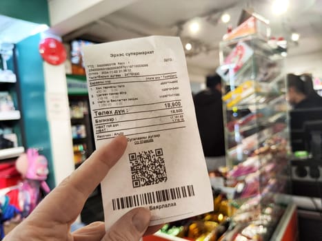 Ulaanbaatar, Mongolia - November 02, 2024: Receipt displays product list and total in Mongolian currency, captured inside a busy grocery store in Ulaanbaatar.