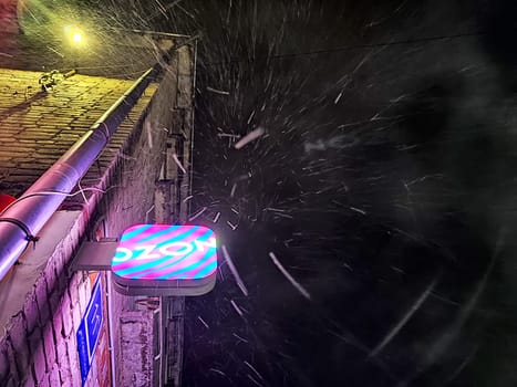 Kirov, Russia - November 15, 2024: Vibrant marketplace logo shines brightly while snowflakes fall gently around it in a nighttime urban setting.