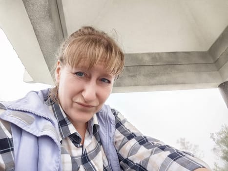 A funny middle-aged woman snaps a selfie in the Ngong Ping 360 cable car, enjoying Hong Kong's stunning views.