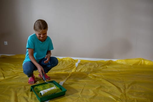 A young girl joyfully paints a room with a roller and tray, displaying her creativity in home improvement