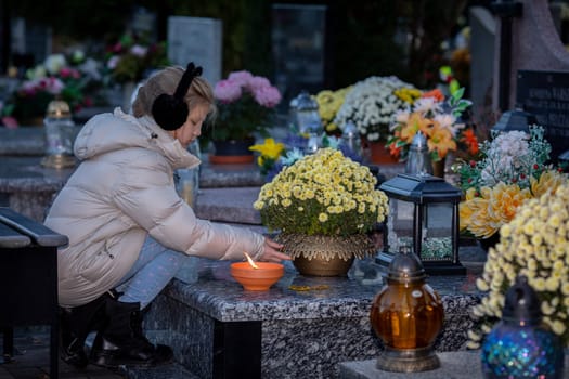 A young child gently places a flickering candle at a floweradorned grave, honoring and cherishing a sweet memory