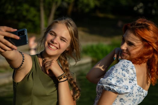 Two friends joyfully capturing a delightful moment with a selfie amidst a beautiful natural setting outside