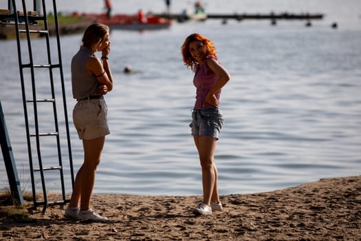 Two friends are enjoying a beautiful sunny beach day, capturing carefree summer vibes by the sparkling water