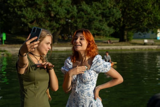 Two cheerful young women joyfully capturing a fun moment near the sparkling water, showcasing their friendship