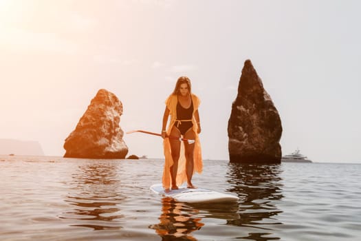 Close up shot of beautiful young caucasian woman with black hair and freckles looking at camera and smiling. Cute woman portrait in a pink bikini posing on a volcanic rock high above the sea