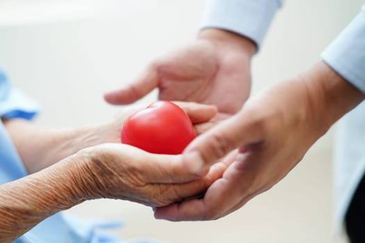 Asian woman doctor holding red heart for health in hospital.