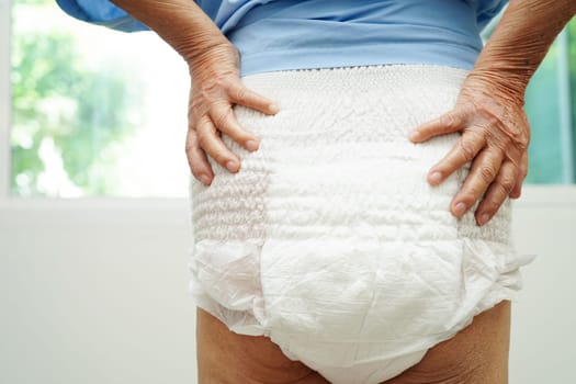 Asian senior woman patient wearing adult incontinence diaper pad in hospital.