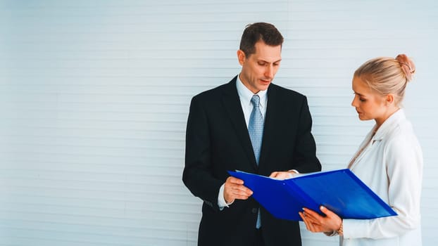 Two business people talk project strategy at office meeting room. Businessman discuss project planning with colleague at modern workplace while having conversation and advice on financial report. Jivy