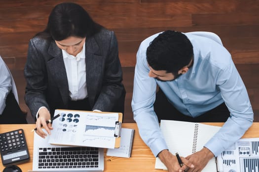 Top view multiracial analyst team use BI dashboard data to analyze financial report on meeting table. Group of diverse business people utilize data analysis by FIntech for business decision. Concord