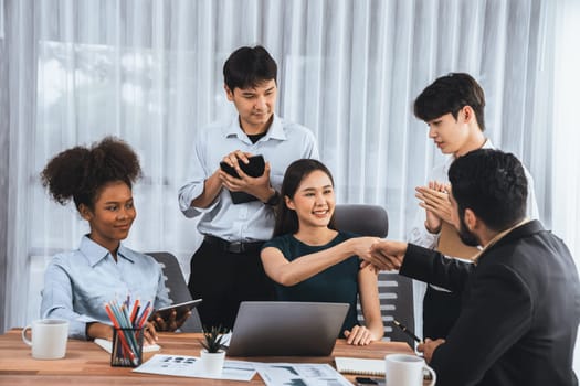 Diverse coworkers celebrate success with handshake and teamwork in corporate workplace. Multicultural team of happy professionals united in solidarity by handshaking in office. Concord