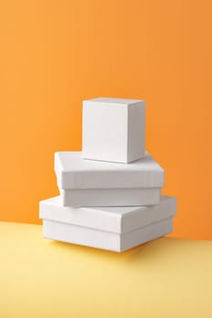 Three closed white jewelry boxes on yellow background close up