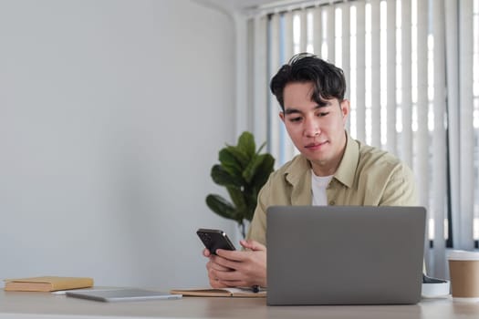 Young happy man smiling while reading his smartphone. Portrait of smiling man reading message with smartphone in home..