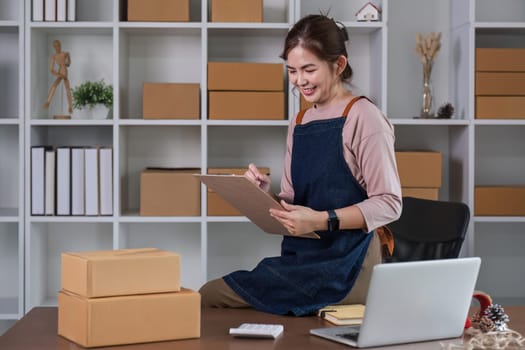 Startup small business entrepreneur SME, asian woman packing cloth in box. Portrait young Asian small business owner home office, online sell marketing delivery, SME e-commerce telemarketing concept.