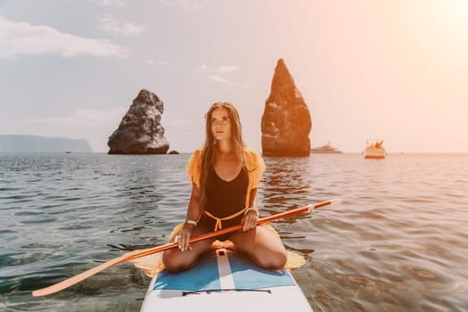 Close up shot of beautiful young caucasian woman with black hair and freckles looking at camera and smiling. Cute woman portrait in a pink bikini posing on a volcanic rock high above the sea