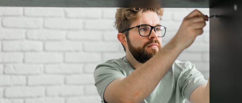 Young attractive man assembles furniture - handwerker and interior objects