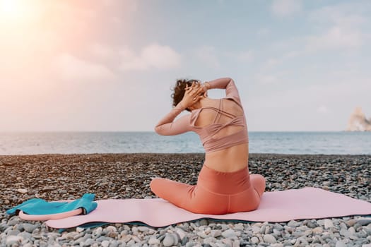 Middle aged well looking woman with black hair doing Pilates with the ring on the yoga mat near the sea on the pebble beach. Female fitness yoga concept. Healthy lifestyle, harmony and meditation.