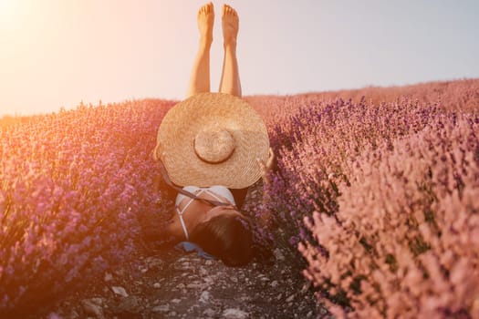 Selective focus. The girls legs stick out of the bushes, warm sunset light. Bushes of lavender purple in blossom, aromatic flowers at lavender fields.