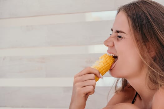 Healthy vegetarian hipster woman in summer outfit eat grilled corn and look to camera. Sexy lady on sea beach sunset or ocean sunrise. Travel, explore, active yoga and meditation lifestyle concept.