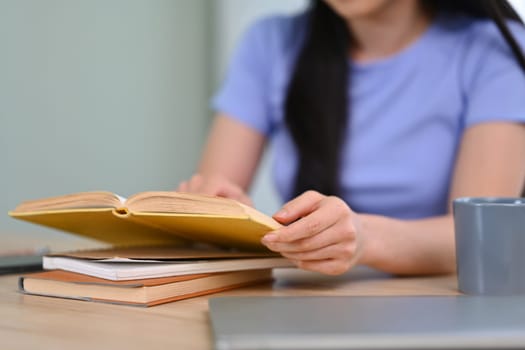 Relaxed young woman wearing casual clothes reading a book at home. Education, leisure and lifestyle concept.