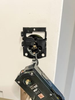 Castle Rock, Colorado, USA-November 23, 2023-A close-up view of the installation of a smart electronic door lock on a white interior door. The person is connecting the wiring and securing the lock mechanism, ensuring proper functionality for keyless entry and enhanced home security. This process is part of a home improvement project to modernize access control.