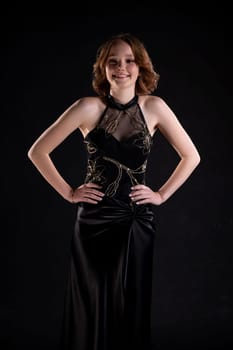 A poised and elegant model is beautifully showcasing a stunning black evening gown set against a dark backdrop