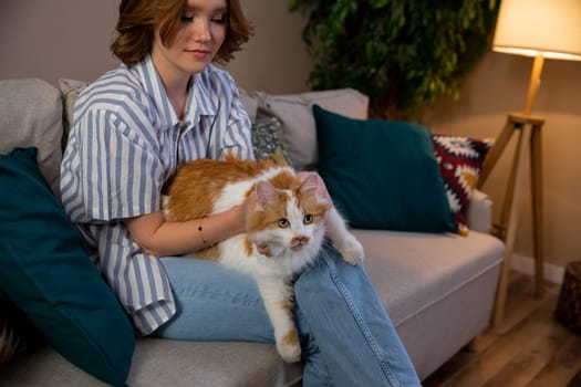 A young girl is happily enjoying some quality time with her beloved pet cat on a stylish and cozy couch at home