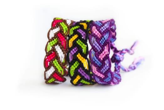 Multicolored woven DIY friendship bracelets handmade of embroidery bright thread with knots isolated on white background